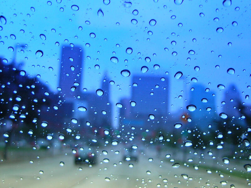 downtown through a wet blue car window